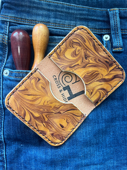 Brown leather cardholder with marbled pattern on a blue denim background